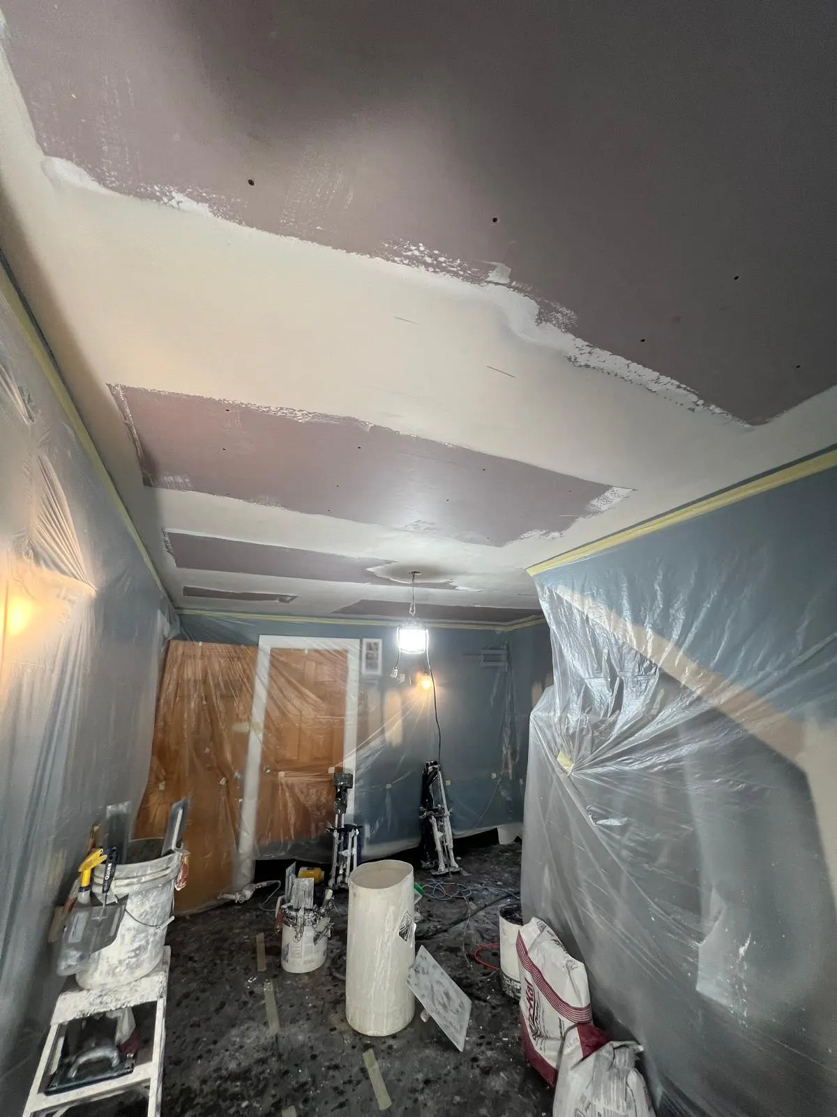 A ceiling being skim coated in progress